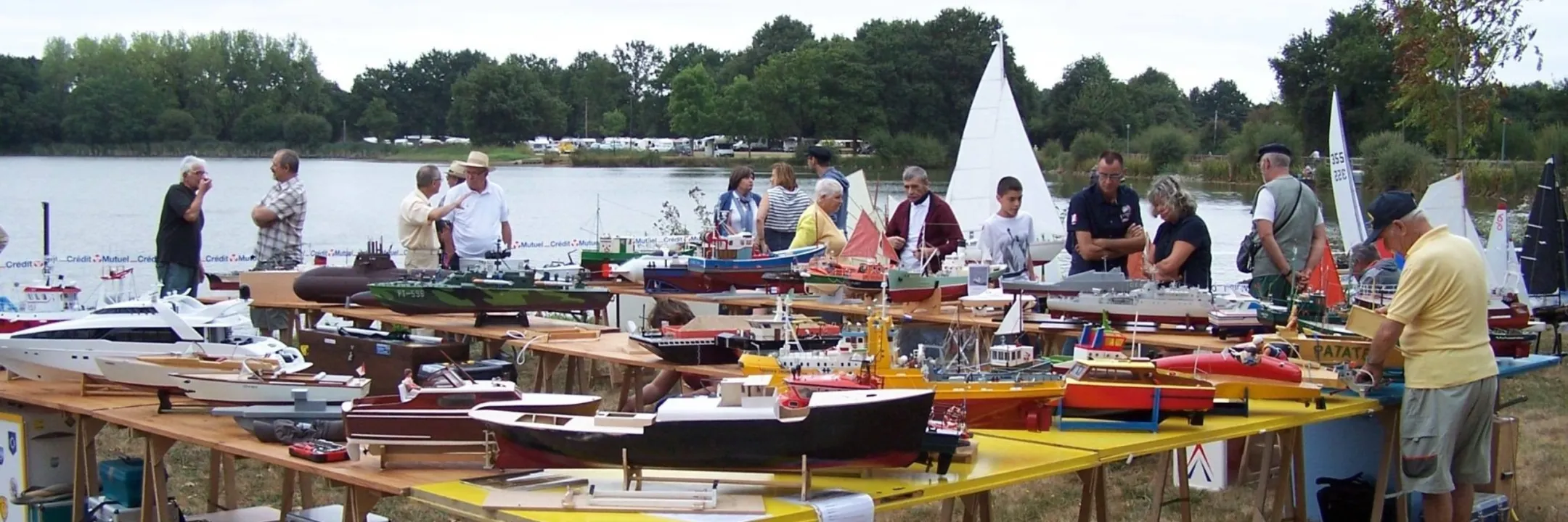 Exposition de maquettes de bateaux sur une grande table devant le lac de la Chausselière à Montaigu-Vendée